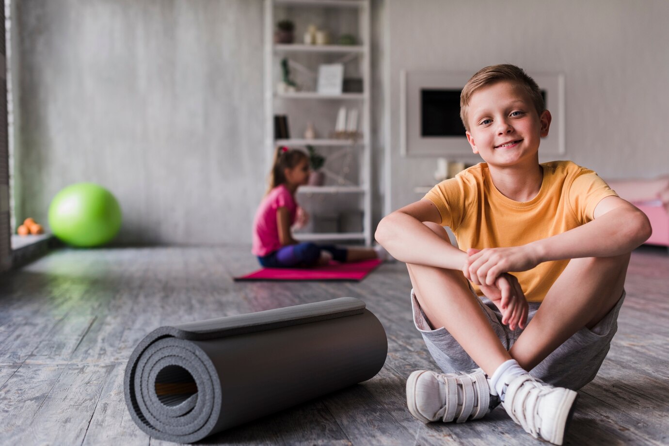 portrait smiling boy sitting near rolled up exercise